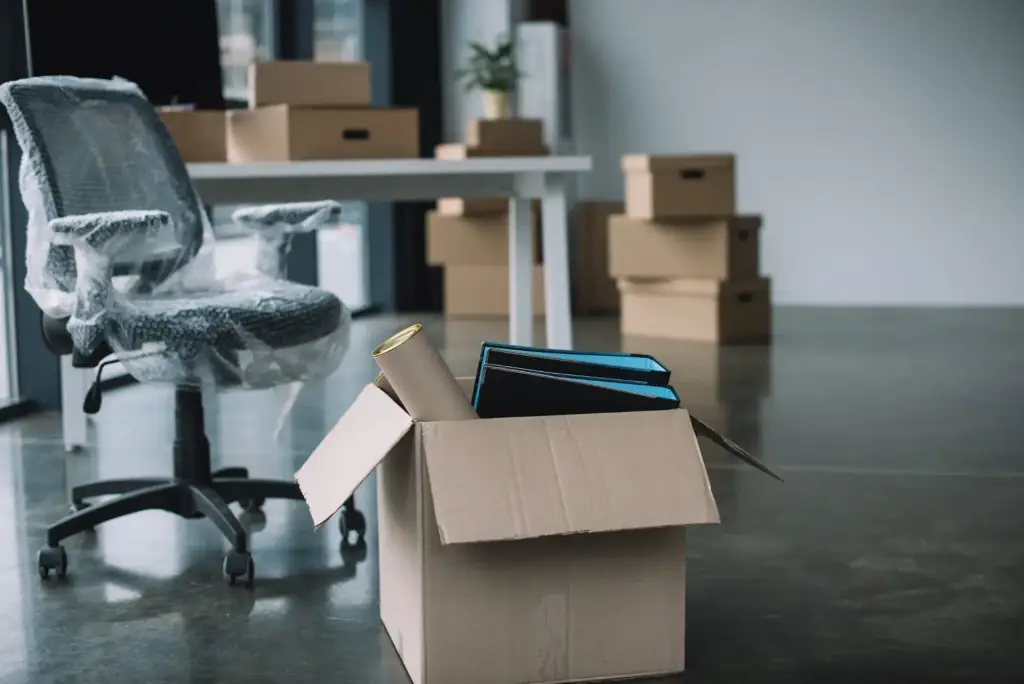 Bürostuhl, Schreibtisch und Umzugskartons in einem Büro vor dem Umzug